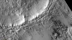 Short dark streaks and fans caused by outgassing of carbon dioxide and dark material. Layers in the crater wall are clearly visible. Image taken with the CTX camera (on Mars Reconnaissance Orbiter).