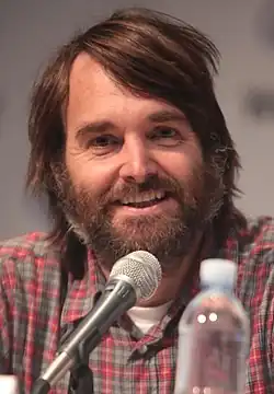A smiling man with a hairy beard.