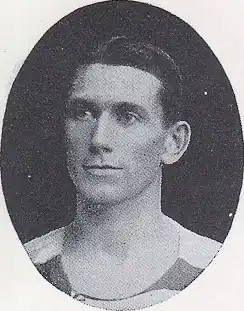 A black and white photograph of a head shot of a Caucasian man with hair slicked to the side.
