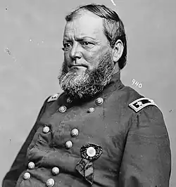 A man with receding hair and a thick beard wearing a military uniform with a ribbon pinned to it