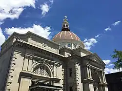 A large neoclassical bank building with a domed roof in front of a blue sky