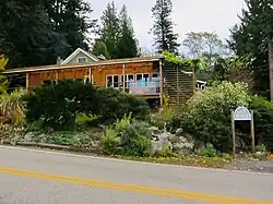A wooden bed and breakfast inn surrounded by greenery.