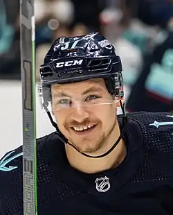 Ice hockey player in a Seattle Kraken jersey smiling