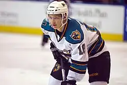Ice hockey player in a Worcester Sharks jersey standing with his knees bent