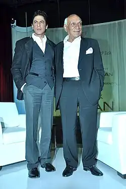 Shahrukh Khan and Yash Chopra are looking away from camera.