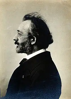 Portrait photograph of Yves Delage, wearing a suit and glasses, sitting in profile to the camera
