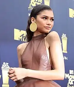 Zendaya with dark, wavy hair styled back