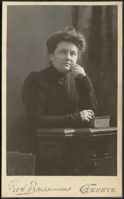 Georgia Lydia Stevens in a dark dress seated at a table with a book
