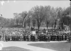 Black and white photograph of people gathered around the statue. Healy Hall is in the background; its entrance is draped in patriotic bunting