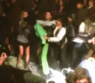 A Hells Angel stabbing Hunter (in a green suit) in the back as other people look on. Patty Bredehoft is standing in front of Hunter.