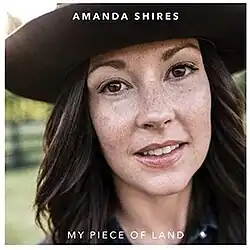 close-up headshot photo of Amanda Shires wearing a wide-brimmed black hat smiling