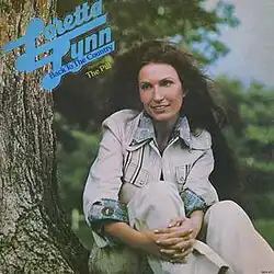photo of Loretta Lynn in denim pantsuit with tree