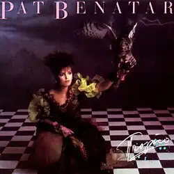 fantasy photo of Pat Benatar wearing colorful dress seated on checkered floor releasing a falcon