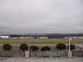 Location of crash of Flight 105 is along runway, perpendicular to the space between the two groups of hangars, slightly to the left of the white parking deck light pole in foreground. Runway 18-36 was extended south after the accident and Village Creek routed through tunnels.
