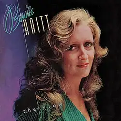 head and shoulders photo of Bonnie Raitt in green with purple background