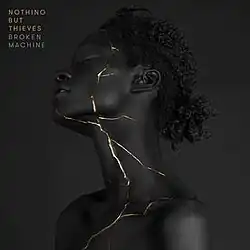A woman with pure black hair and skin has golden cracks running down one side of her body