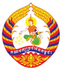 Logo of the Cambodian People's Party, featuring an angel spreading flowers, surrounded by golden rice stalks and a demi cogwheel, and party's name in Khmer on the ribbon