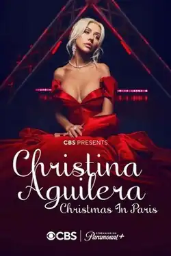 Christina Aguilera sitting down in front of the Eiffel Tower