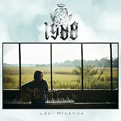 photo of Lori McKenna with guitar seated in front of window overlooking marsh