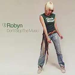 An image of a blonde woman wearing a green tank top and blue jeans. The names of the single and the artist are superimposed over the image.