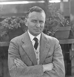 Man in a light-colored suit with crossed arms looking at the camera