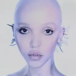 Close-up portrait of bald Twigs with minimal makeup and decorative ear accessories