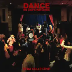 Various people dancing in front of a stage with the quintet playing on it against a blue curtain.