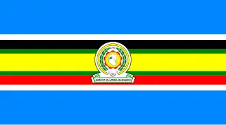 Nine horizontal strips coloured (from top to bottom): blue, white, black, green, yellow, green, red, white, then blue. The emblem of the EAC is placed in the centre.