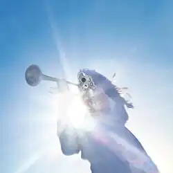 A long-haired figure in white robes holding a trumpet in one hand and aiming a gun at the camera with their other hand