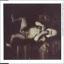 Sepia photo of a crying baby lying on its back on a wooden floor
