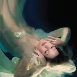 Cover artwork of the deluxe edition of Higher Than Heaven, showing Goulding against a dark blue background, with her eyes closed and her hair and light fabric floating around her