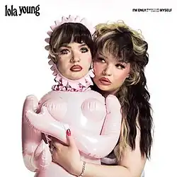 Lola has her arms around a blow-up sex doll of herself