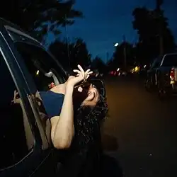 The cover features a person driving in the night with their head sticking out of a car, upside down, and a cigarette in their hand.