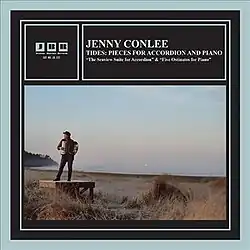 A photo of Conlee with an accordion, standing on a small platform on the shore