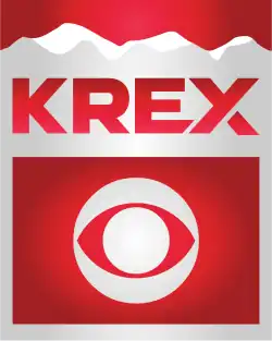 Silver and white mountains silhouetted against a red background with the red letters KREX. The X has a cut on its lower right leg. Beneath in a red box is a silver CBS eye logo.