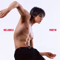 A shirtless Yeonjun with short dark hair appears in profile against a plain white background, leaning forward with one arm raised and the other lowered, wearing black trousers and looking downward.