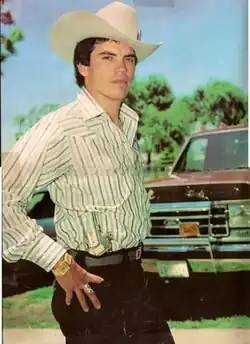 Chalino Sánchez poses with a holstered M1911 in front of a plane