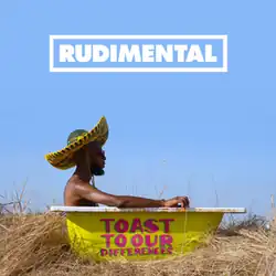 In a stack of hay, a man wearing a green and yellow sombrero sits on a bathtub with its exterior painted in yellow with the album's title painted on it.
