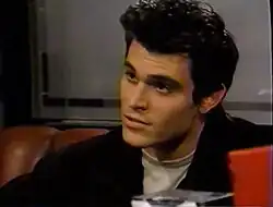 A dark-haired caucasian male sitting in a diner booth.