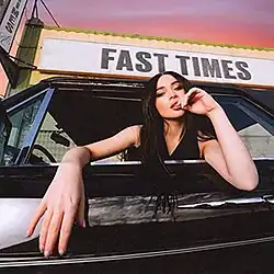 Sabrina Carpenter in the car outside with the sign of the song title behind the sunset.