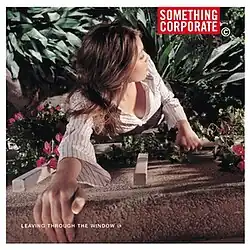 A woman climbing down the side of a wall into bushes and flowers
