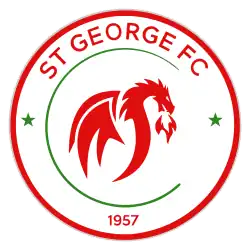 A red and green on white circular badge depicting a dragon breathing fire.