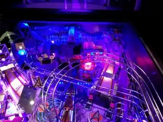 upper part of playfield of Star Trek: The Next Generation pinball machine showing the three ramp entrances, three sinkholes, and models of ships