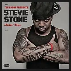 The grey cover with black borders has Stevie Stone wearing a black tank top and backward baseball cap, crossing his tattooed arms under his armpits. The artist's name appears on the top-left corner colored in black, and both "Tech N9ne Presents" and the album title book end it, colored in red.