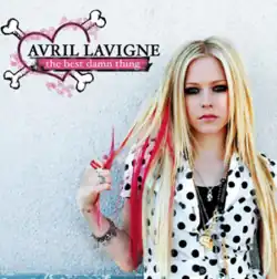 The album cover for The Best Damn Thing sees Avril Lavigne standing against a white wall. Wearing a white shirt with black dots on it, she is gripping strands of her hair. On the top left is a heart with two bones protruding out of it and text reading the artist's name in all uppercase and the album title in all lowercase, albeit against a pink background.