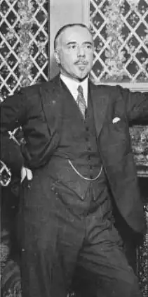 middle-aged man in three-piece suit; he has a small neat beard and moustache