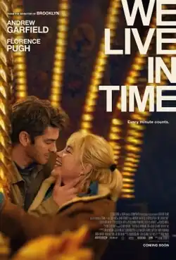 Illuminated by the lights of a carousel, a man and a woman embrace each other.