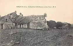 Carte postale sépia de bâtiments prenant appui sur un mur ruiné.