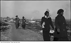 Photo noir et blanc d'un groupe de femmes noires marchant dans un secteur en ruine.