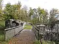 pont de bois au-dessus d’un fossé, menant à une ouverture dans une construction défensive en pierres